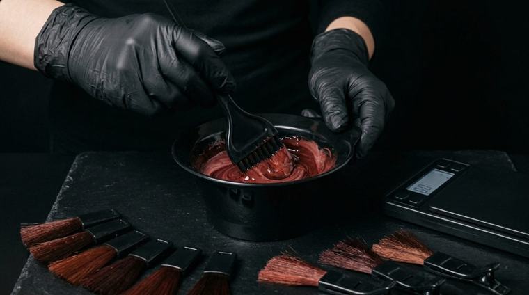 Manos de colorista mezclando tinte junto a una balanza